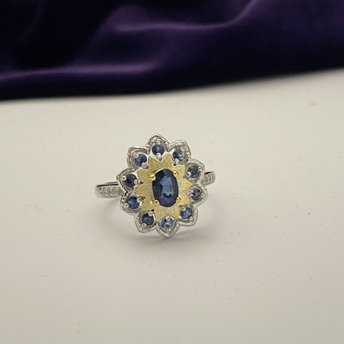 30 - A BEAUTIFUL 18CT GOLD PLATED NATURAL SAPPHIRE CLUSTER RING, featuring central oval cut sapphire, sur... 