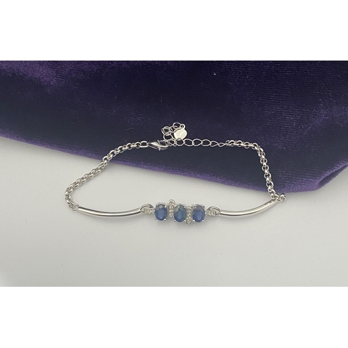 40 - A SPARKLING 18CT GOLD-PLATED SILVER THREE STONE SAPPHIRE BRACELET, featuring three oval cut vibrant ... 
