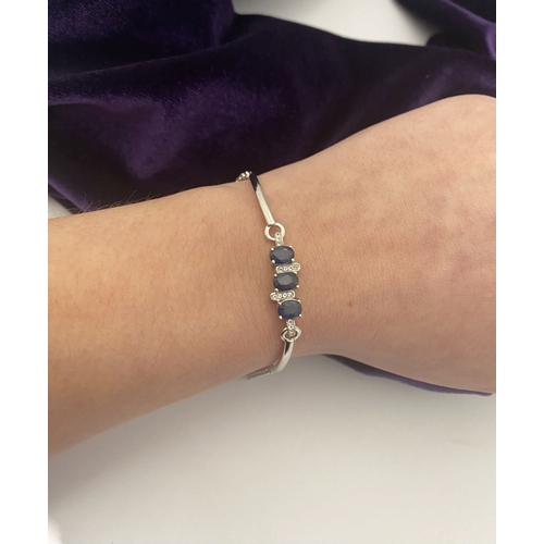 40 - A SPARKLING 18CT GOLD-PLATED SILVER THREE STONE SAPPHIRE BRACELET, featuring three oval cut vibrant ... 
