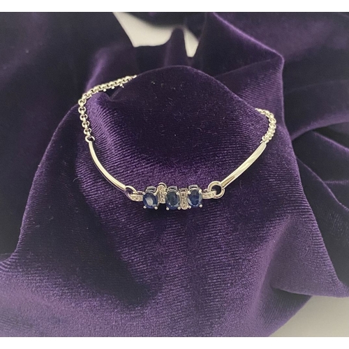 40 - A SPARKLING 18CT GOLD-PLATED SILVER THREE STONE SAPPHIRE BRACELET, featuring three oval cut vibrant ... 