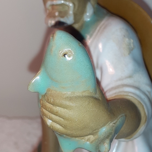 7 - Chinese mudman ornament holding fish. Stamp marks underneath indecipherable.  Approx 19cm tall. No d... 