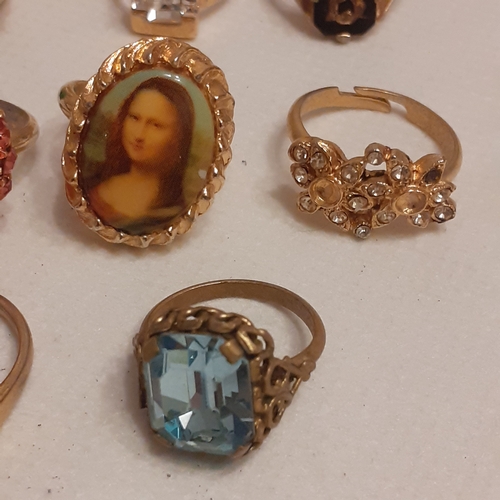 15 - A collection of gold coloured rings to include designs with Mona Lisa, a variety of coloured stones ... 