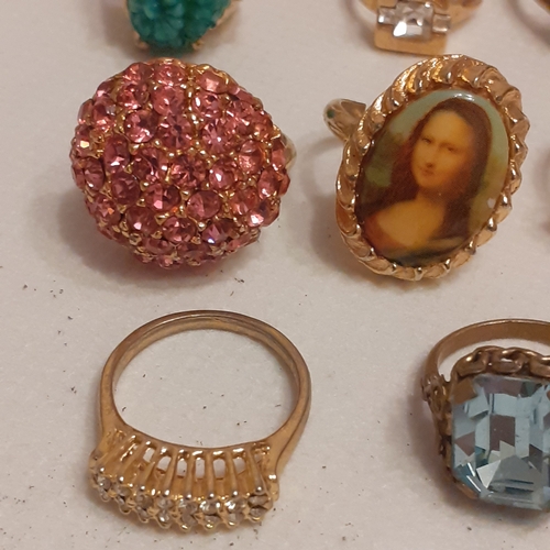 15 - A collection of gold coloured rings to include designs with Mona Lisa, a variety of coloured stones ... 