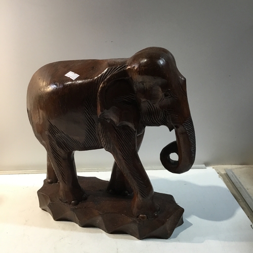 169 - Carved wooden elephant on plinth - 30cm tall