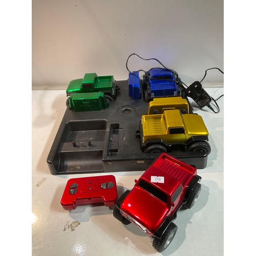 25 - Red, Yellow, Green and Blue remote control trucks with large charging dock