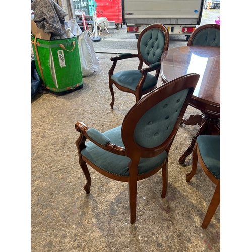 253 - Polished oval dining table with rich wood finish and ornate pedestal base. Paired with six tufted, u... 