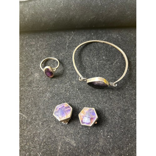 16 - Sterling silver bangle, ring (size O) and earrings with decorative purple & clear central stone set ... 