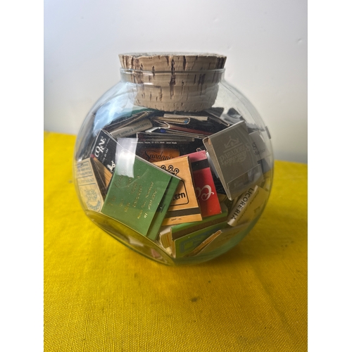 29 - Small glass jar full of various match books