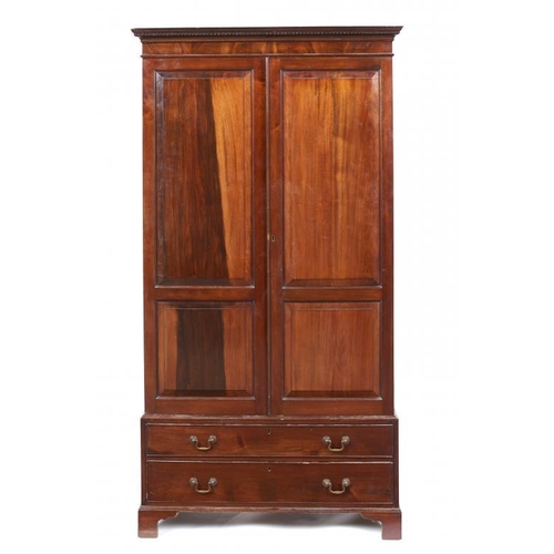 973 - A HIGHLY FIGURED MAHOGANY WARDROBE, EARLY 20TH C with dentil cornice, the doors with raised and fiel... 