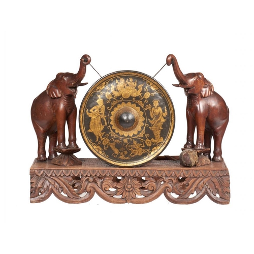 998 - A BURMESE CARVED HARDWOOD AND GILT BRASS DINNER GONG, EARLY 20TH C  the base   with a central flower... 