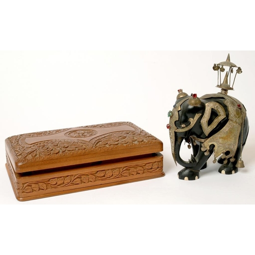 392 - AN INDIAN CARVED EBONY ELEPHANT ORNAMENT, CAPARISONED IN COLOURED GLASS - JEWELLED SILVERED BRASS, 2... 