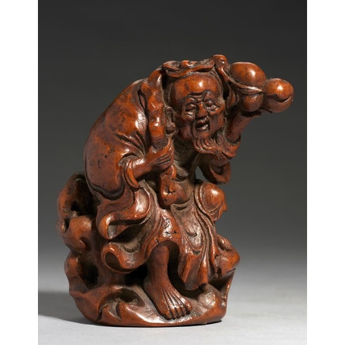 555 - A CHINESE CARVED BAMBOO FIGURE OF SHOU-LAO on a rock, holding a peach bough in his left hand and cra... 