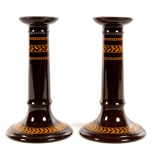 216 - A PAIR OF WEDGWOOD BROWN GLAZED EARTHENWARE CANDLESTICKS WITH ACORN AND OAK LEAF OCHRE BANDED DECORA... 