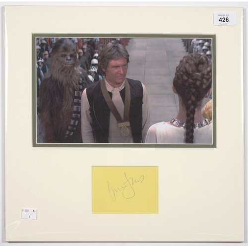 426 - STAR WARS INTEREST. HARRISON FORD, PIECE SIGNED, MOUNTED WITH A COLOUR PHOTOGRAPH, 38 X 39CM