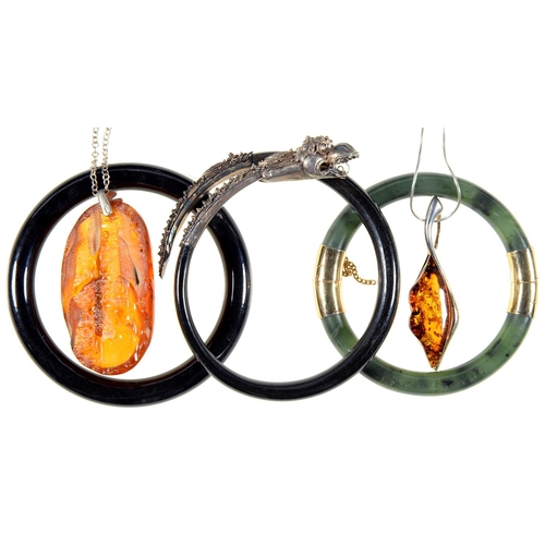 115 - A GILTMETAL MOUNTED NEPHRITE BANGLE, 75MM DIAM, TWO OTHER BANGLES AND TWO AMBER PENDANTS, ONE SILVER... 