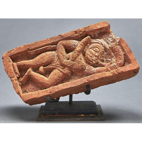 1068 - An Indian fired clay brick with deity in relief, 19th c, 24cm l, metal stand