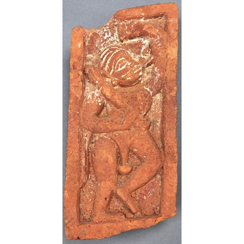 1068 - An Indian fired clay brick with deity in relief, 19th c, 24cm l, metal stand