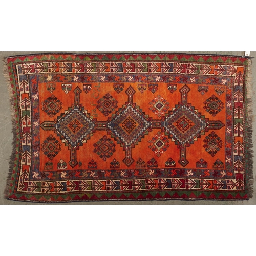 1445 - A Kazak style rug, the orange field worked with three geometric medallions, barber medallions and st... 