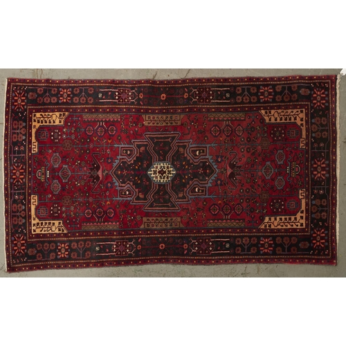 1451 - A modern Caucasian bordered rug, the claret field worked to the centre with a black, pink, turquoise... 