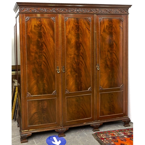 1463 - A mahogany triple wardrobe in George III style, flared cornice above a frieze applied shell and foli... 