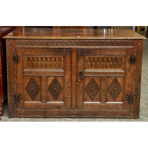 1473 - An oak  cupboard, 19th c,  with leaf carved frieze and carved three panel doors with H hinges, on st... 