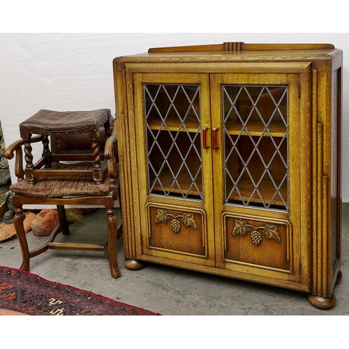 1487 - An art deco style oak display cabinet with shallow upstand, enclosed by a pair of lead glazed doors ... 