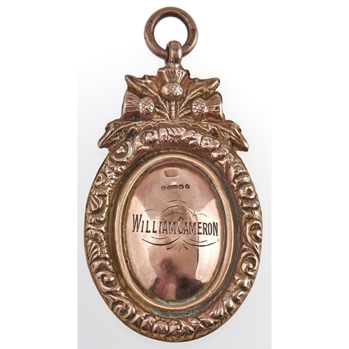 203 - An oval 9ct gold prize watch fob shield, surmounted by thistles, with contemporary engraved inscript... 