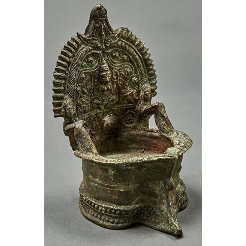 982 - A Nepalese bronze oil lamp , the shaped back cast with seated cross legged female Bodhisattva within... 