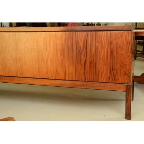 1355 - A rosewood sideboard, c1970,  fitted with drawer and cutlery tray, enclosed by plain or louvred... 