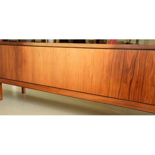 1355 - A rosewood sideboard, c1970,  fitted with drawer and cutlery tray, enclosed by plain or louvred... 