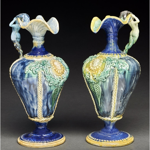 63 - A pair of French Palissy ware ewers, late 19th c, of pear shape with mermaid handle and moulded grot... 