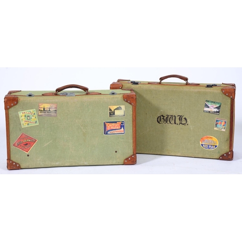 522 - Two leather trimmed green canvas suitcases, second quarter 20th c, 66cm l