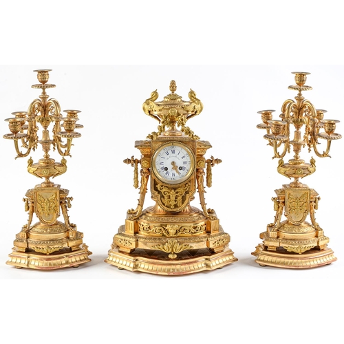 948 - An ormolu garniture de cheminee, 19th c, the ornate case with urn finial with bird handles and pinea... 