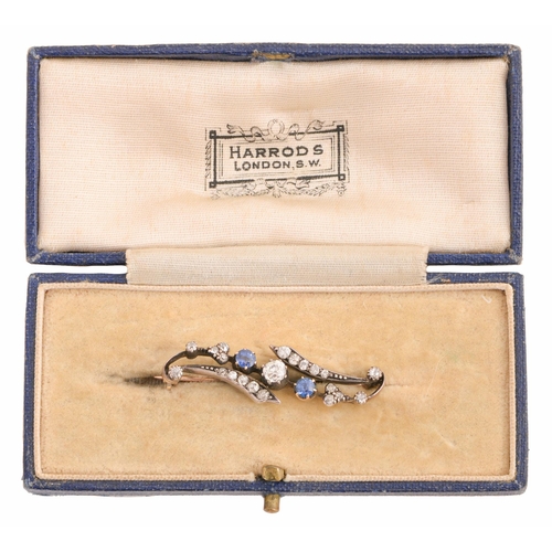 109 - A sapphire and diamond brooch, early 20th c, of scrolling design, in gold, 38mm l, 3.5g... 