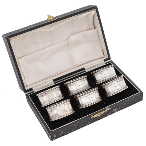 408 - A set of six George V oval silver napkin rings, with engraved borders and beaded rims, by John Rose,... 