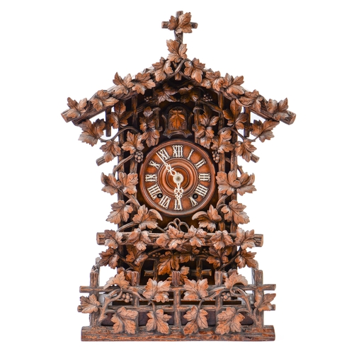 900 - A Swiss walnut cuckoo clock, late 19th c, in the form of a chalet embowered with fruiting vines cent... 