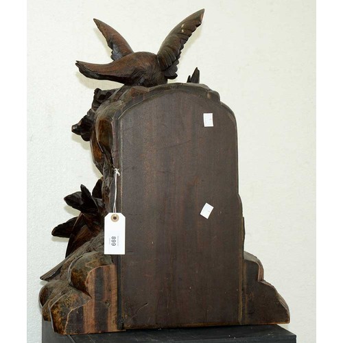 899 - A Swiss limewood cuckoo clock, late 19th c, in the form of a rocky crag surmounted by an eagle swoop... 