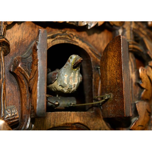 900 - A Swiss walnut cuckoo clock, late 19th c, in the form of a chalet embowered with fruiting vines cent... 