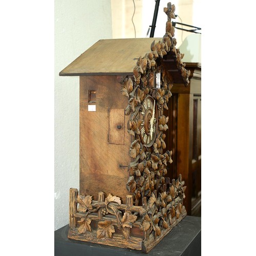 900 - A Swiss walnut cuckoo clock, late 19th c, in the form of a chalet embowered with fruiting vines cent... 