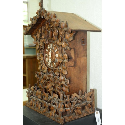 900 - A Swiss walnut cuckoo clock, late 19th c, in the form of a chalet embowered with fruiting vines cent... 