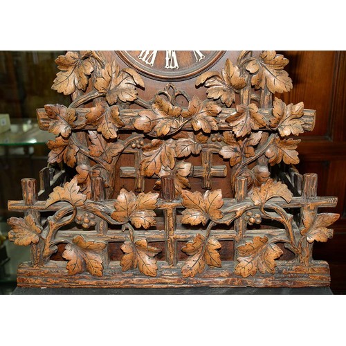 900 - A Swiss walnut cuckoo clock, late 19th c, in the form of a chalet embowered with fruiting vines cent... 