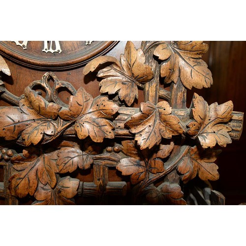 900 - A Swiss walnut cuckoo clock, late 19th c, in the form of a chalet embowered with fruiting vines cent... 