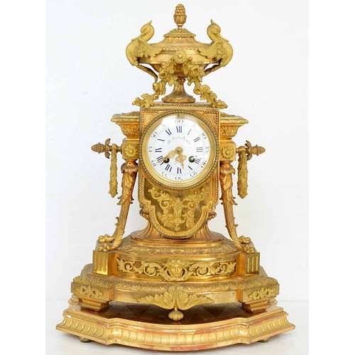 948 - An ormolu garniture de cheminee, 19th c, the ornate case with urn finial with bird handles and pinea... 