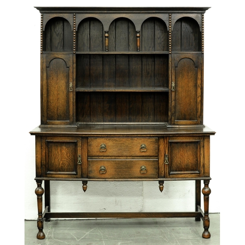 565 - An oak dresser, c1930, the boarded rack with spice cupboards, 200cm h; 55 x 151cm