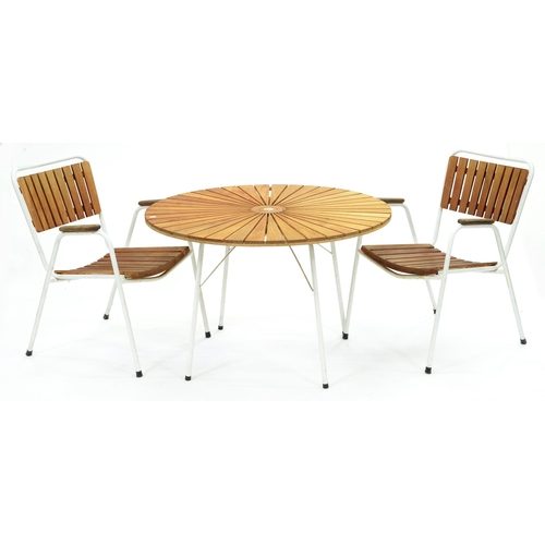 629 - A teak and white painted tubular metal garden table and pair of elbow chairs, c1970, table 64cm h; 1... 