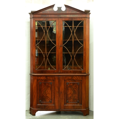 1023 - A George III mahogany standing corner cabinet, with open triangular pediment, the upper doors with s... 