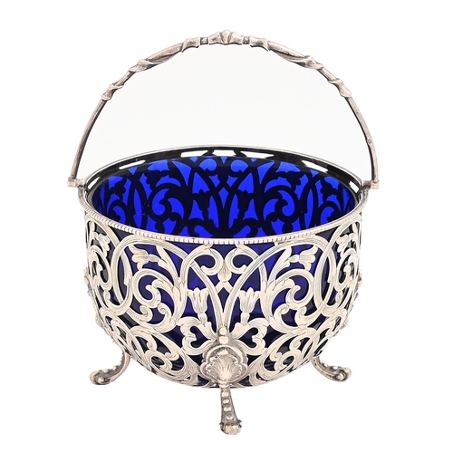 329 - A Victorian pierced and engraved silver sugar basket, with beaded rim and swing handle, blue glass l... 