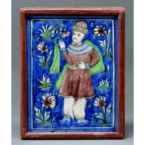 599 - A Persian tile,  early 20th c, painted with a man flanked by flowers on a blue ground, 21 x 16cm, fr... 