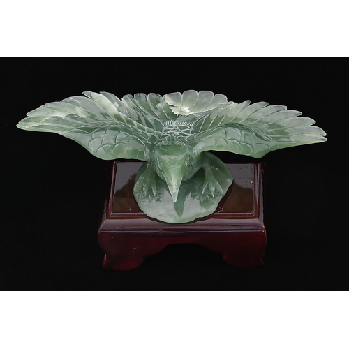 663 - A Chinese jade carving of an eagle, wingspan 25cm, wood stand