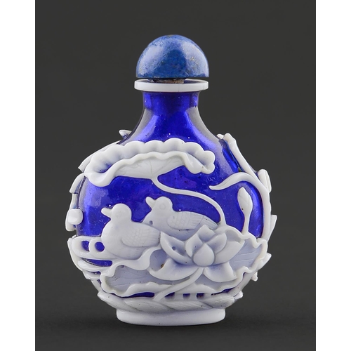 73 - A Chinese cameo glass snuff bottle, 20th c,  in deep blue glass overlaid in white and carved with du... 